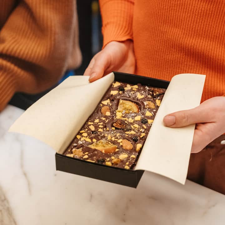 Plan rapproché d'une personne qui présente un plateau de chocolats artisanaux fourrés aux fruits à coque et aux fruits secs.