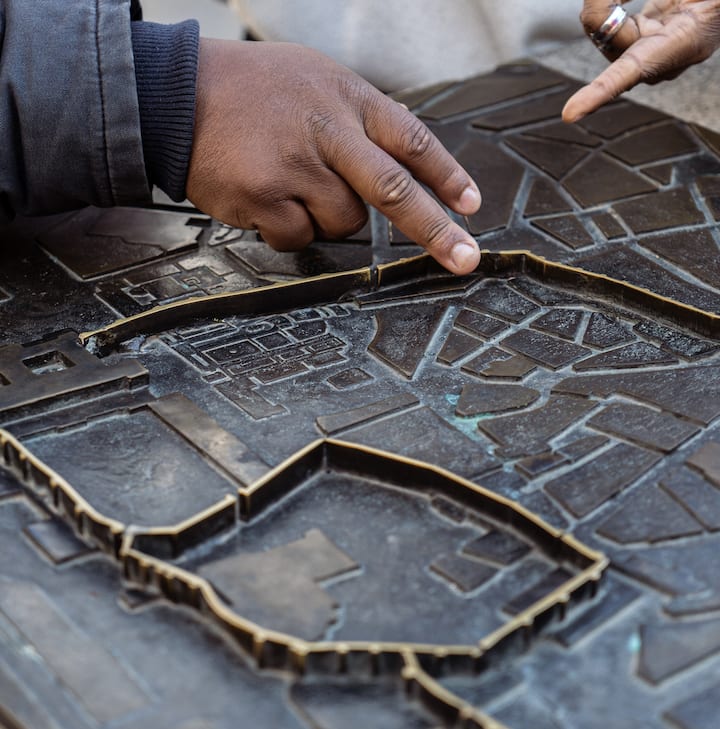 Close-up of two hands engaging with a tactile map, showing detailed streets and landmarks.
