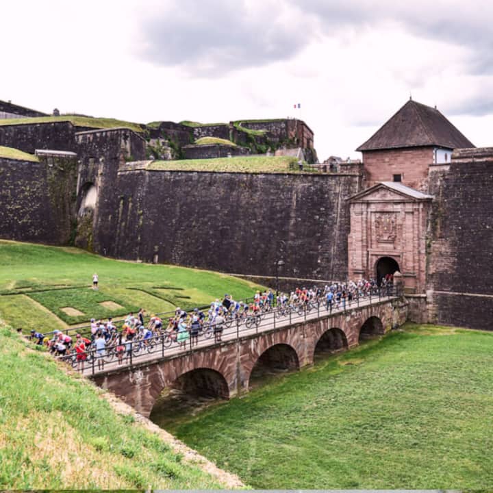 Les coureurs du Tour de France traversent un pont historique en ville