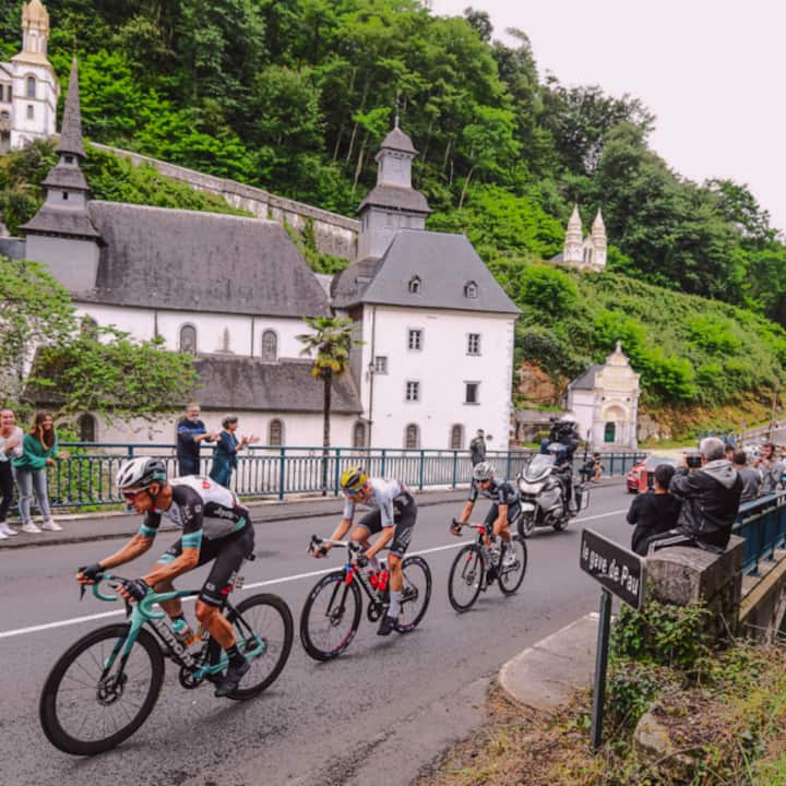 Trois coureurs du Tour de France traversent une ville à vélo