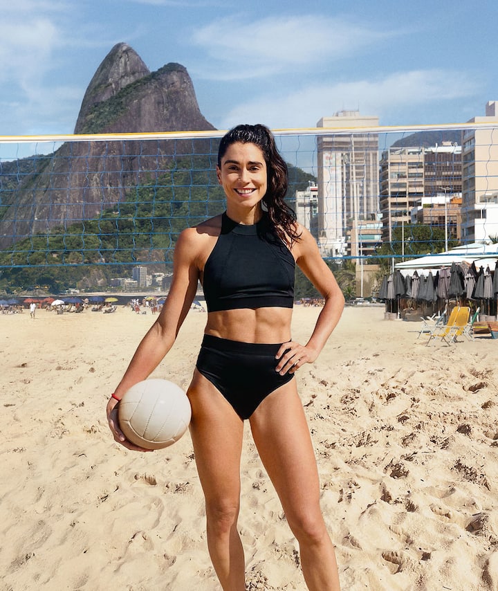 A beach volleyball player poses in front of Rio's mountainous backdrop.