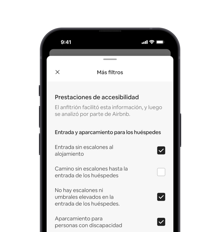 En un celular se muestra la ventana Más filtros, que es uno de los muchos filtros de búsqueda. Hay un encabezado de sección que dice “Prestaciones de accesibilidad”. Debajo, las prestaciones están agrupadas por zona, como “Entrada para huéspedes y estacionamiento”. Hay casillas de verificación donde podés seleccionar las prestaciones que quieras.