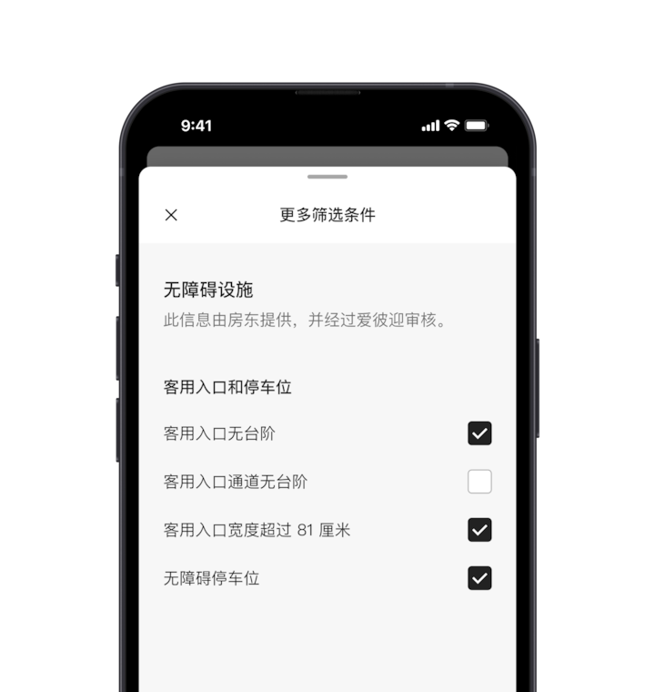 一部手机，屏幕上显示「更多筛选条件」弹出窗口，它是众多搜索筛选条件中的一项。其中一个版块标题为「无障碍设施」。下面的无障碍设施按区域分组，如「客用入口和停车位」。你可以点击复选框，选择所有你需要的无障碍设施。