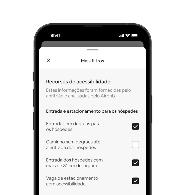 Um celular exibe a sobreposição Mais filtros, uma das muitas opções nos filtros de busca. Há um título de seção que diz "Recursos de acessibilidade". Abaixo, os recursos de acessibilidade são agrupados por áreas como "Entrada e estacionamento para os hóspedes". Você pode escolher quantos recursos quiser marcando as caixas de seleção.