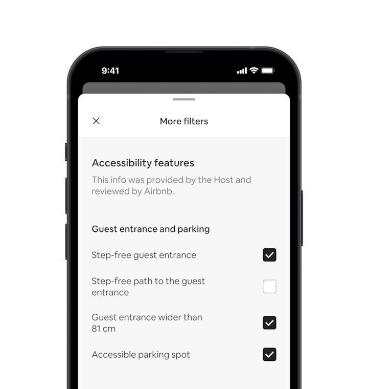 A mobile phone displays the More filters overlay, which is one of many search filters. There is a section heading that reads ‘Accessibility features’. Below that accessibility features are grouped by areas like ‘Guest entrance and parking’. There are tickboxes where you can select as many features as you want.
