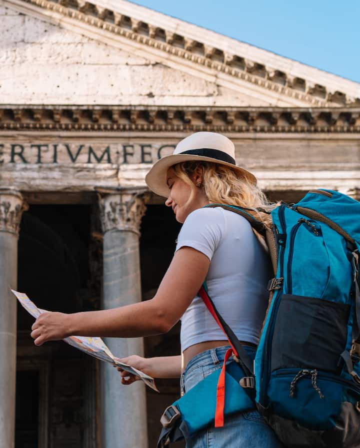 Side view of a person reading a map while standing near the Pantheon, highlighting travel and discovery in a historical setting.