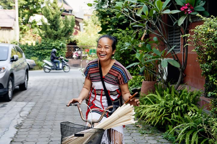 A local Thai woman smiling at the camera with a bicycle