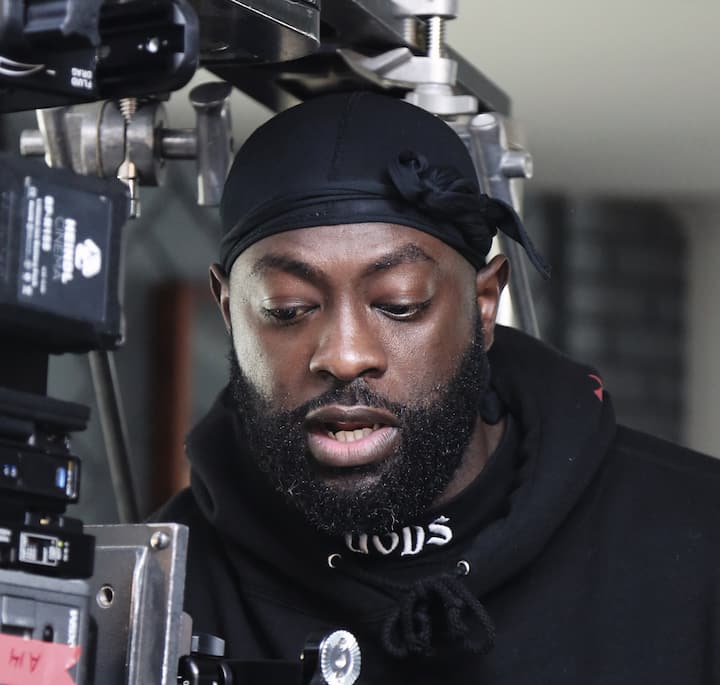 Professional camera equipment and lighting setup in a studio environment, with part of a person wearing a black hoodie visible.