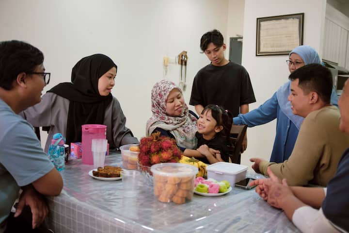 Amirul's family gathered around a dinner table with food on the table