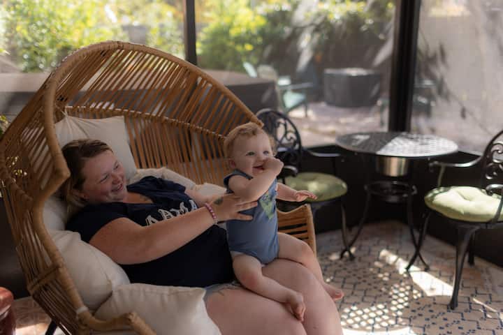Skylyn, an Airbnb.org guest, is holding her 10-month-old baby in a chair at the Airbnb they evacuated to from the flood.