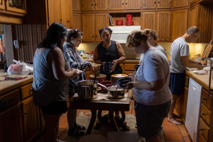 A group of volunteers from All Hands and Hearts are cooking in the kitchen of their Airbnb.org stay.