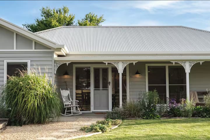 Charming cottage with a front porch, rocking chair, and garden.