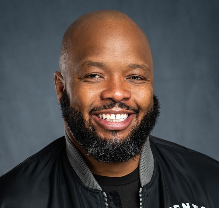 KevOnStage shown in a black jacket with visible text on the sleeve, promoting game night and karaoke at his Los Angeles studio.