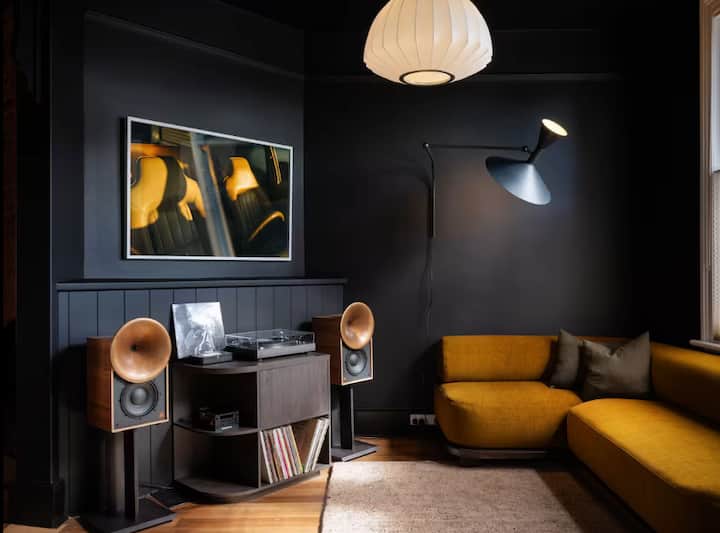 Stylish dark living room with mustard sofa and vintage speakers.