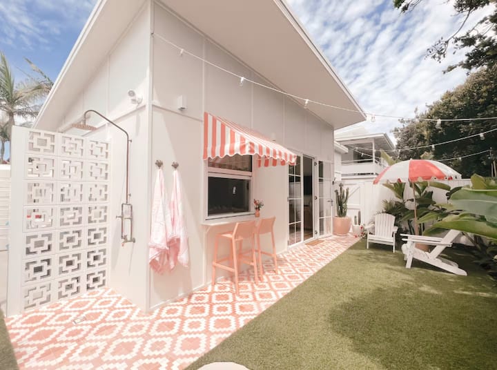 Bright beach-style house with outdoor shower, striped awning, and patio.