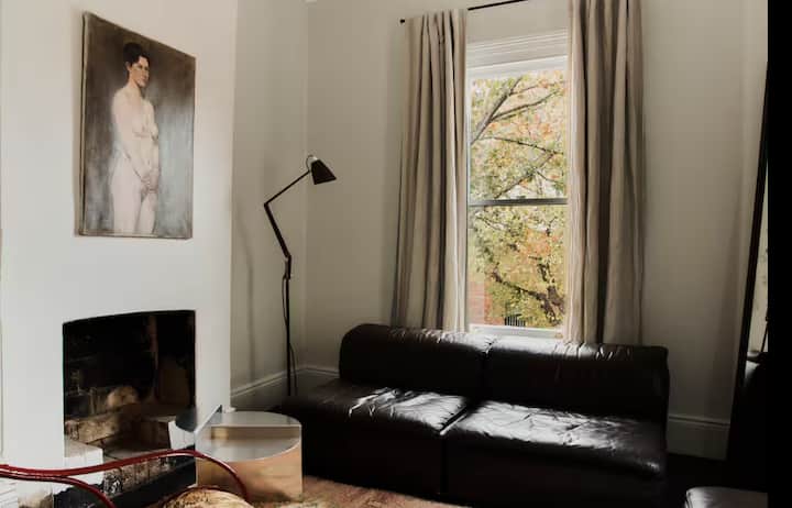 Living room with dark leather sofa, fireplace, and large window.