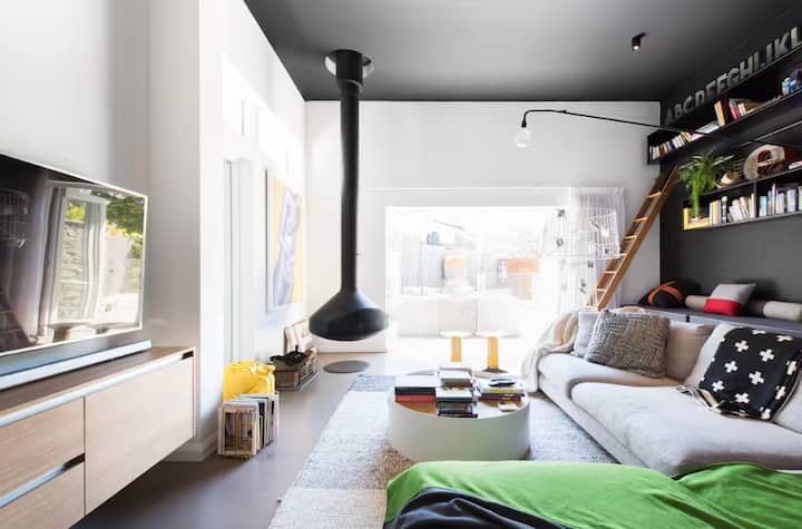 Bright living room with modern fireplace, loft bookshelf, and cozy sofa.