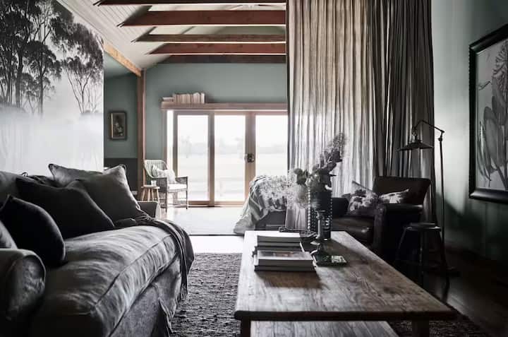 Rustic living space with exposed beams, muted tones, and cozy furnishings.