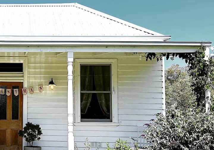 White weatherboard cottage with a wooden door
