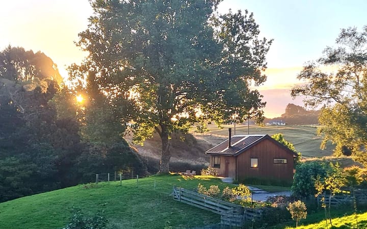 Sunset over rustic cabin in rolling countryside