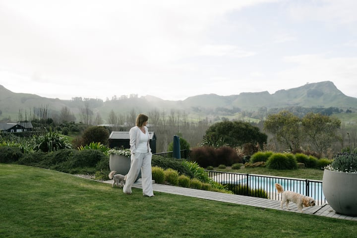Woman in white suit walking dogs by poolside garden