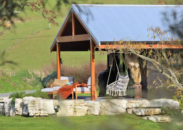 Rustic outdoor pavilion with hammock chair and loungers