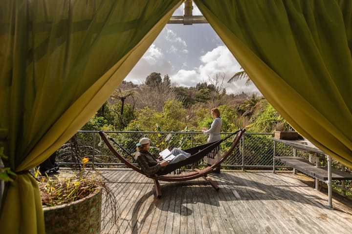 Couple relaxing on deck hammock in lush forest setting