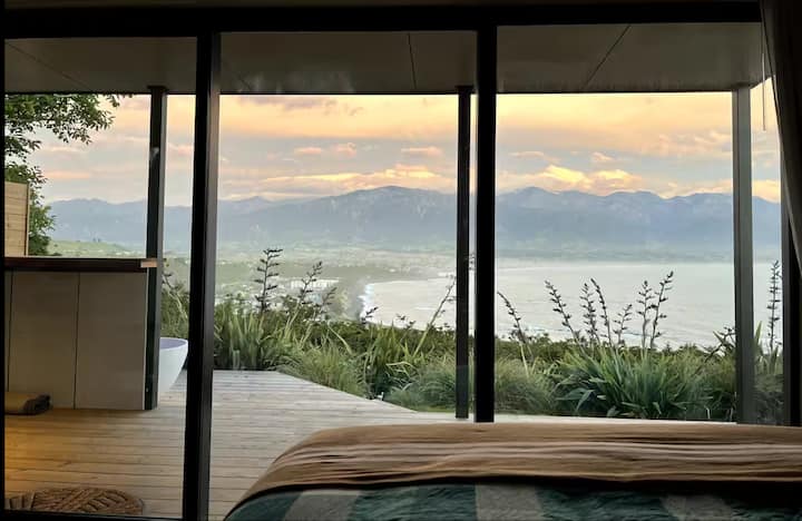 Bedroom view of ocean and mountains at golden sunset