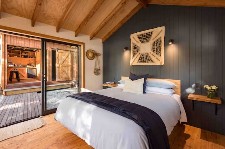 Cozy wooden cabin bedroom with sliding doors opening to an outdoor kitchen
