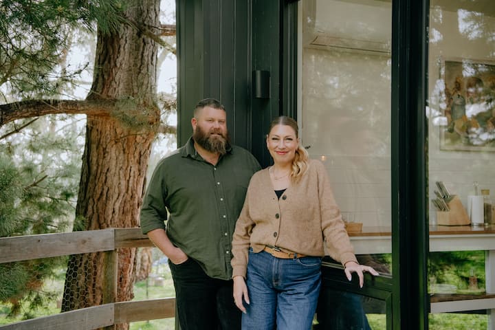 Couple standing outside modern black cabin