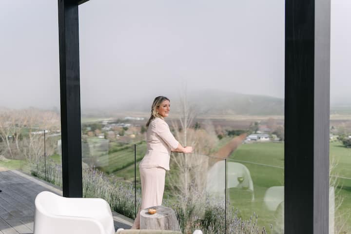 Woman enjoying misty vineyard balcony view