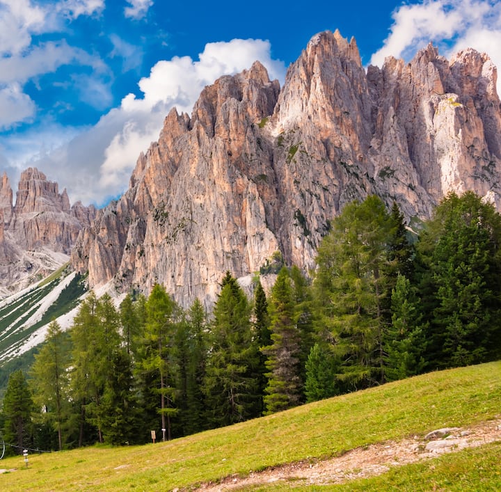 Le Dolomiti del Veneto, in Italia, Patrimonio mondiale dell'UNESCO circondato da foreste lussureggianti sotto un cielo azzurro parzialmente nuvoloso.