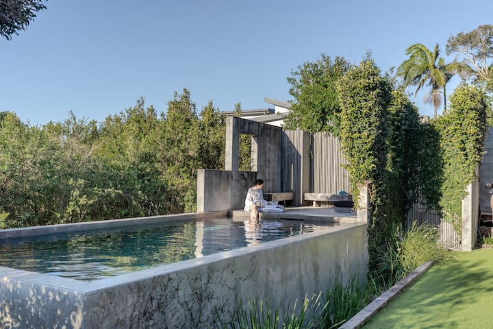 Modern poolside retreat with greenery and person relaxing