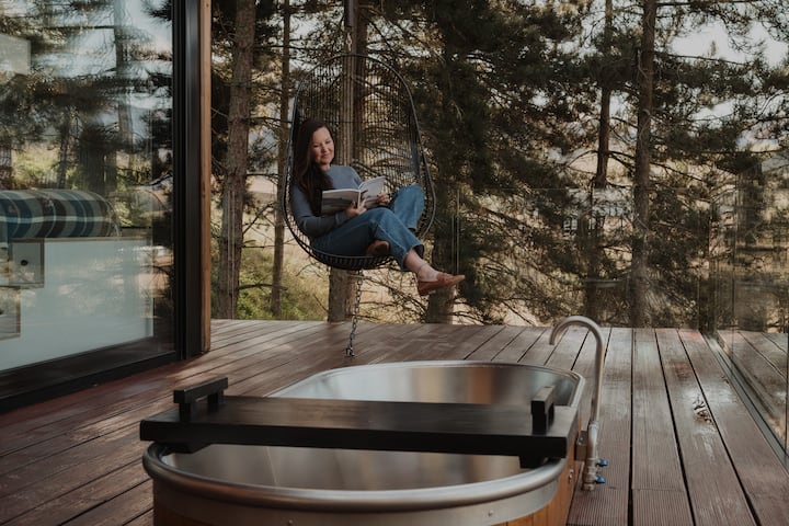 Woman sitting in hanging chair outside on deck in forest