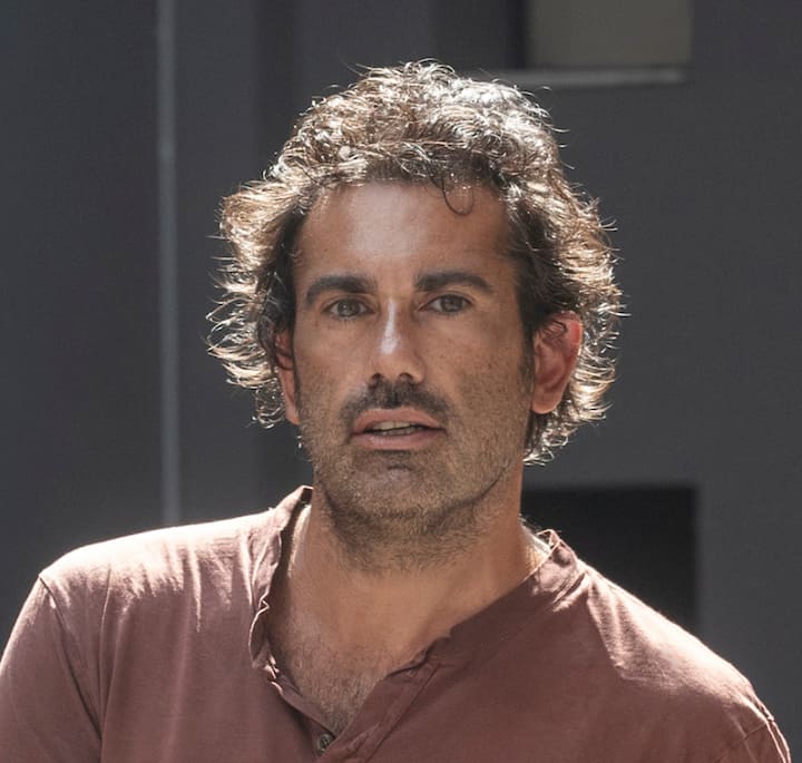 Close-up of a man with curly hair and a brown shirt, appearing in natural light, associated with the guided evening museum tour led by Luca Lo Pinto in Milan.
