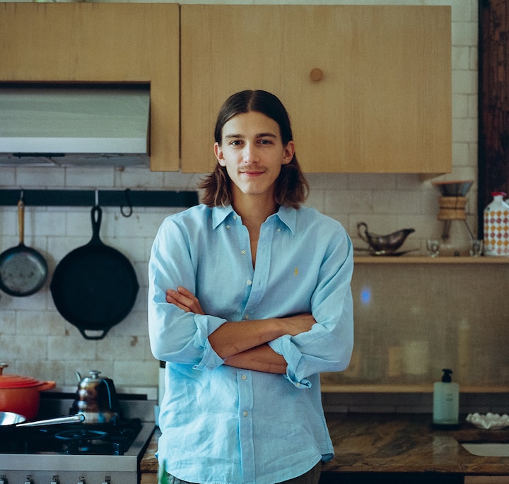 A kitchen featuring wooden cabinets, a countertop with ceramic dishes, and a stovetop with a red pot and kettle, located in a rustic hand-sculpted studio in New York City.