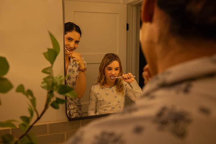 Mother and daughter brush teeth at bathroom sink