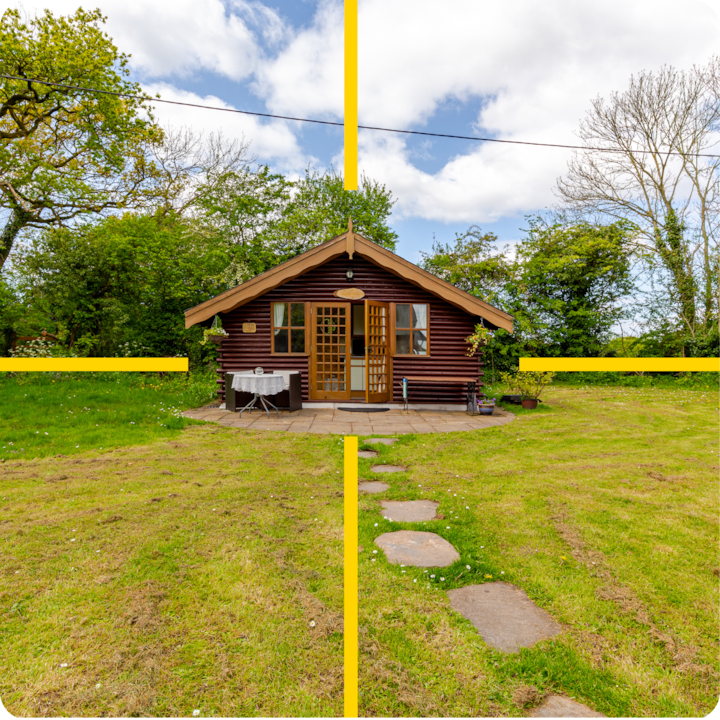 Un chalet cosy au style symétrique, entourée d'une végétation luxuriante, avec une allée en pierres menant à l'entrée et une petite terrasse avec une table et des chaises sous un ciel bleu nuageux.