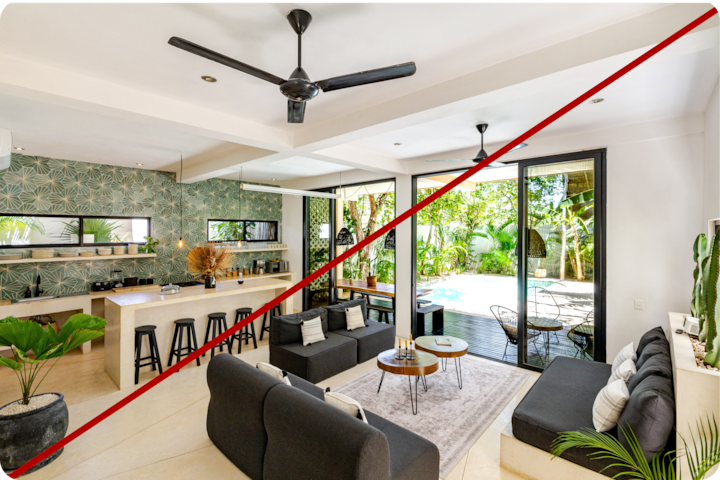 Salon moderne et ouvert sur une cuisine au papier peint tropical, une table et des tabourets de bar, menant à un grand patio extérieur avec de la verdure et une piscine.