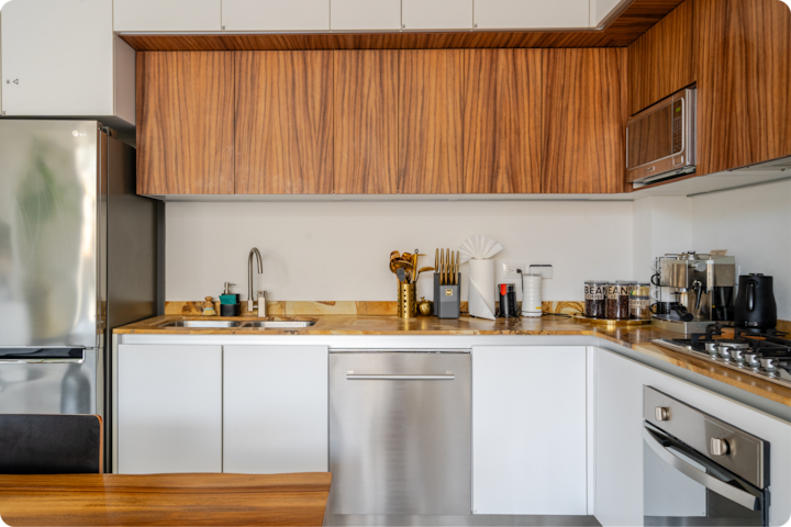 Cuisine moderne avec des placards en bois, un réfrigérateur en acier inoxydable et un lave-vaisselle, dotée d'un plan de travail élégant avec un évier et divers appareils électroménagers.