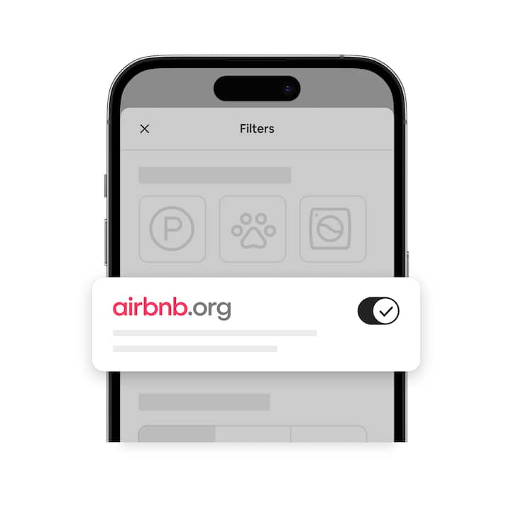 Phone with a muted image of Airbnb’s search screen and a bright, enlarged image of Airbnb.org’s logo next to a toggle button.