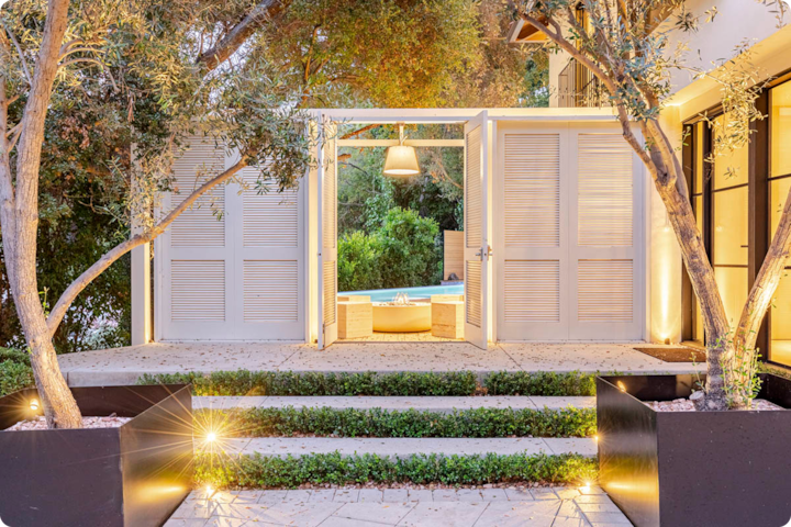 Espace extérieur avec un coin salon paisible et une petite piscine, entouré d'une végétation luxuriante et de marches d'accès éclairées.