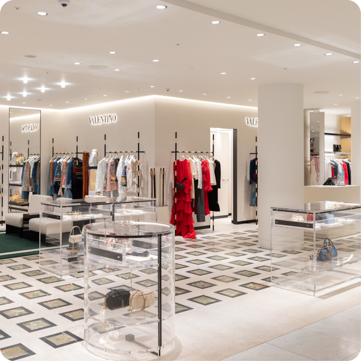 Intérieur d'une boutique de luxe proposant des vêtements et accessoires Valentino, avec des présentoirs lumineux et un décor moderne.