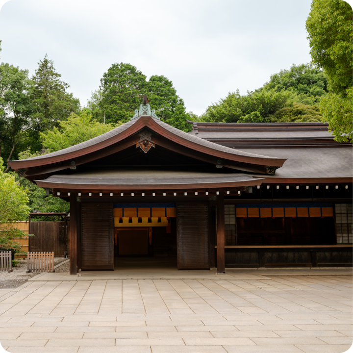 Photo d'un sanctuaire japonais traditionnel en bois entouré d'arbres verdoyants par temps nuageux, mettant en valeur le cadre extérieur paisible.