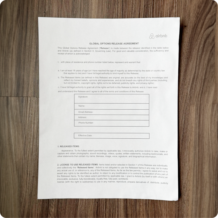 Un formulaire imprimé de l'Accord de décharge global d'Airbnb est placé sur une surface en bois. Il comporte des champs pour la signature, le nom, l'adresse e-mail, l'adresse postale, le numéro de téléphone et la date d'entrée en vigueur.