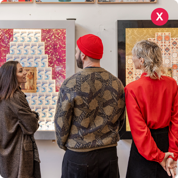 Trois personnes se tiennent devant des œuvres d'art encadrées colorées, l'une représentant une mosaïque de cartes à jouer et l'autre un collage de motifs bleu et blanc sur un fond à motifs rouges.