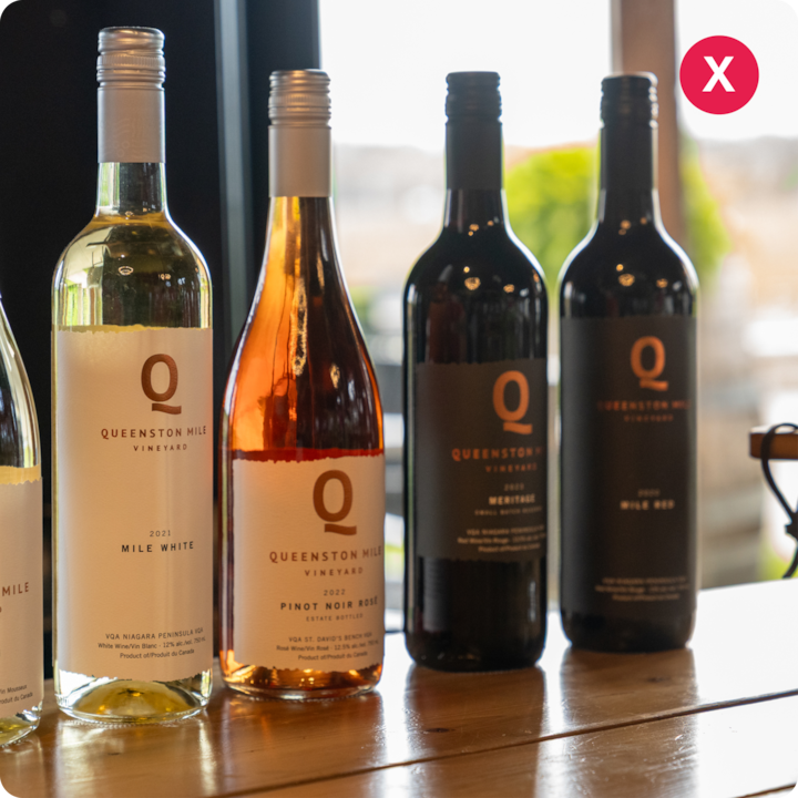 Quatre bouteilles de vin, dont des vins blancs, rosés et rouges, sont présentées sur une table en bois avec un paysage extérieur flou en arrière-plan.