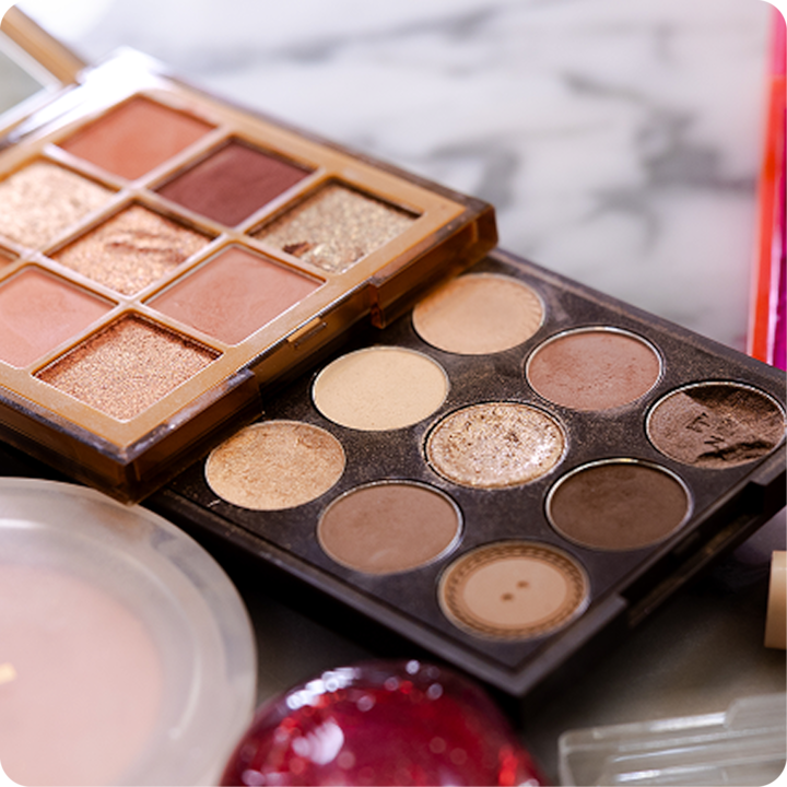 Deux palettes de maquillage présentant un éventail de teintes neutres et chaudes, y compris des finitions mates et chatoyantes, sont présentées sur une surface en marbre.