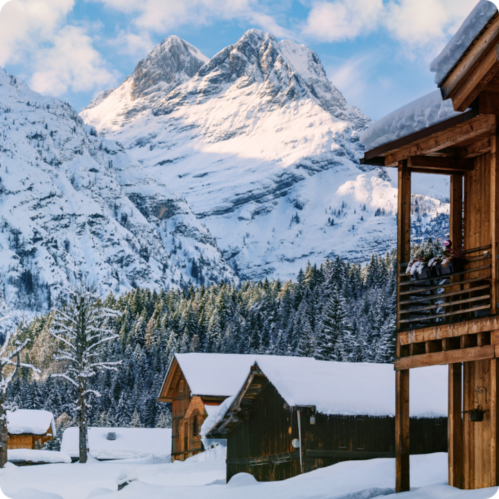 Snow covered ski cabins in front of craggy snowy mountains