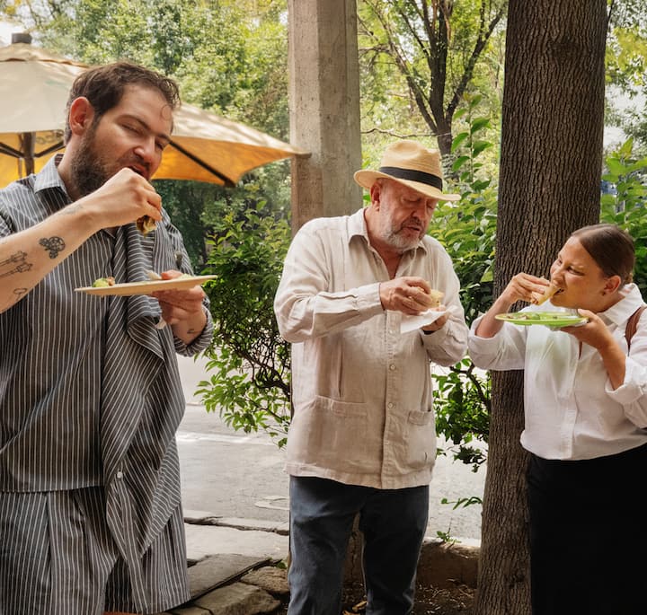 An image of three people eating street tacos